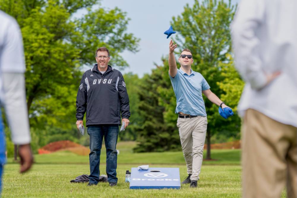 Two players stand throwing bags during a game